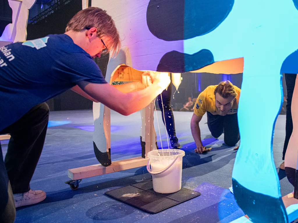 Deltagare i Yrkeskampen mjölkar i en ko-attrapp