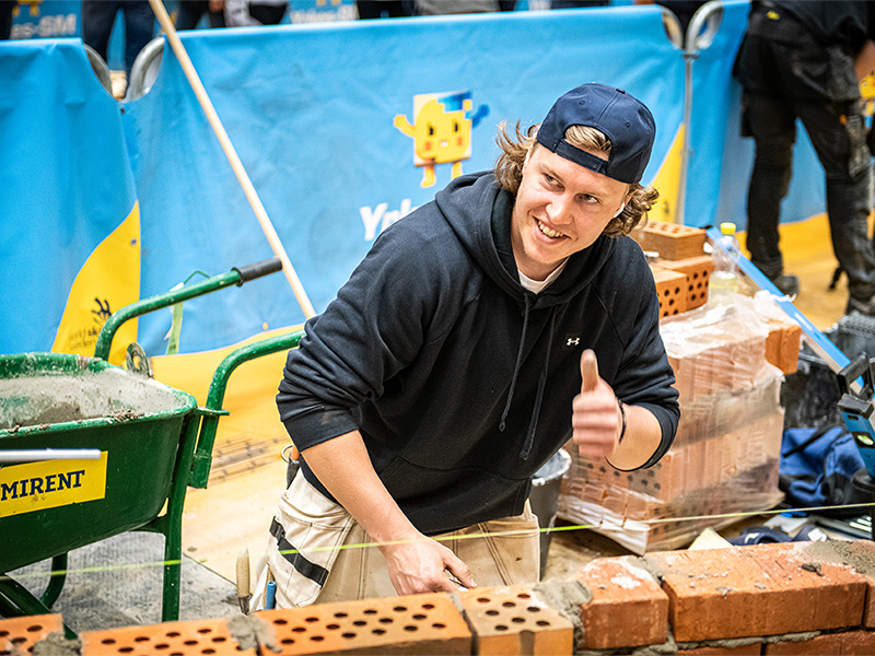 A competitor in brick laying makes a thumbs up