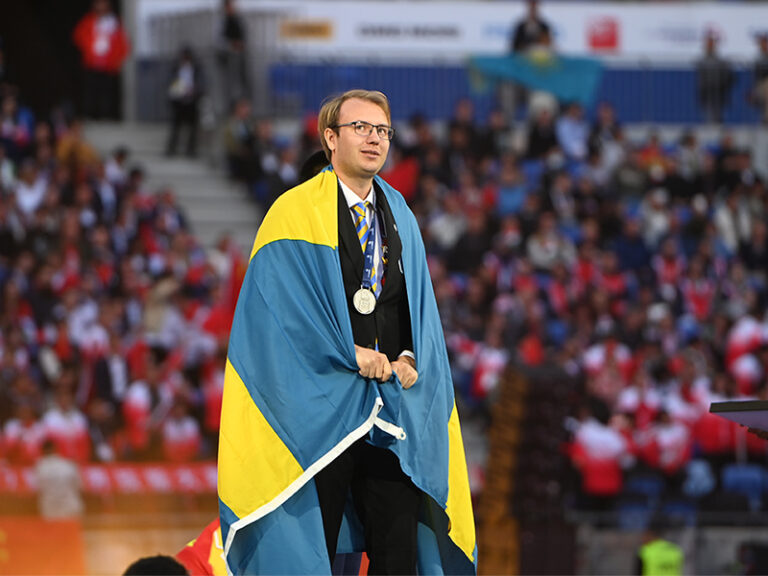 The Swedish second place winner of WorldSkills stands in front of a stadium full of people at WorldSkills Lyon
