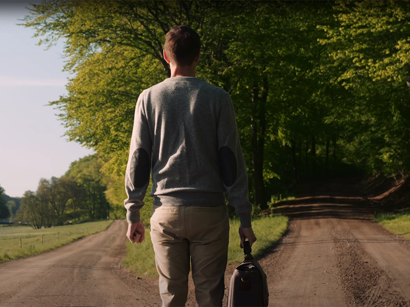 A man standing at a cross road, trying to choose a path, on a sunny day.
