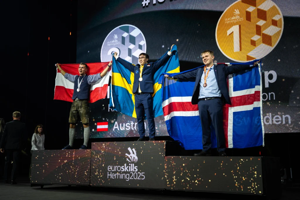 Philip Svensson waves the Swedish flag on top of the price podium with a gold medal around his neck