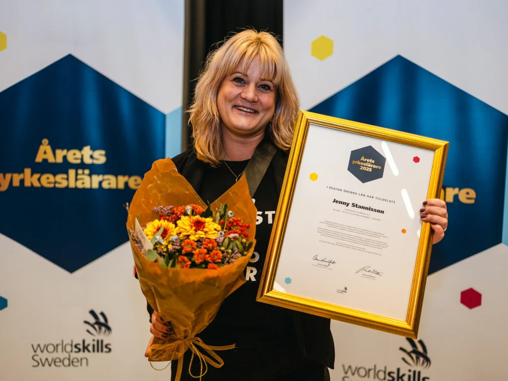 Jenny Stannisson håller upp en bukett med blommor och diplomet för Årets yrkeslärare